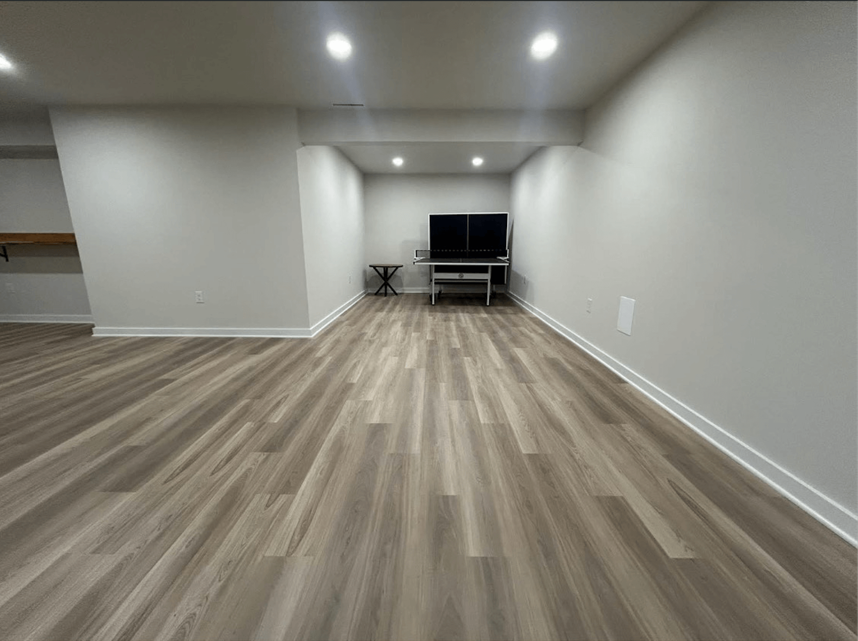 Finished basement with luxury vinyl flooring and recessed lighting